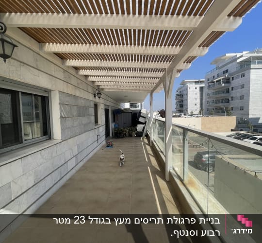 מרפסת עם פרגולה מעץ ובניינים ברקע
